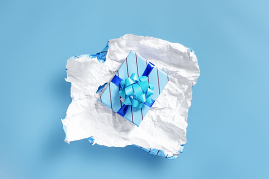 Image of gift box lying on a piece of crumpled gift wrap paper