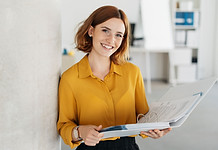 Eine Frau in einem Büro mit einem Aktenorder in der Hand.