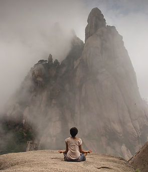 Woman meditating peacefully at cloudy mountain base. Represents spiritual serenity, nature connection, and inner calm.