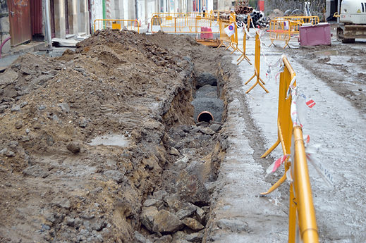 Long excavated dirt trench with a drainage pipe laid along the bottom