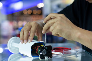 Person repairing a security camera, using a screwdriver. Focus on hands and tools