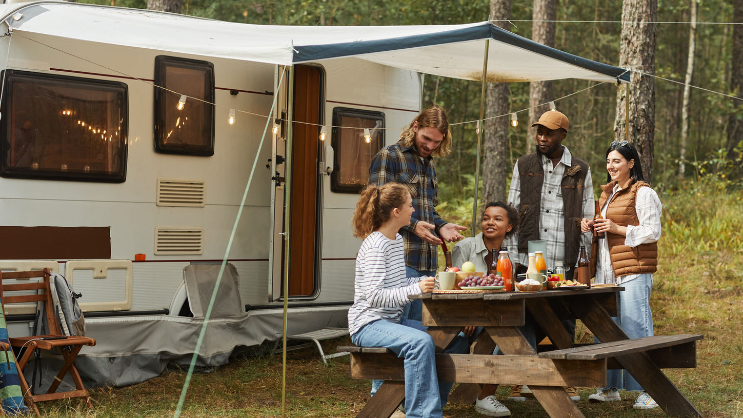 Group of friends camping and enjoying a meal outdoors.
