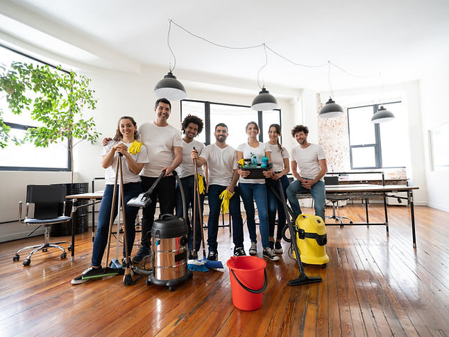 Cleaning contractors at an office smiling at camera holding cleaning products and industri