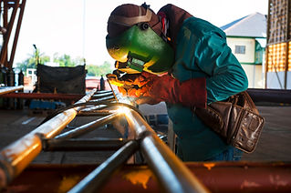 Welder working on metal pipes