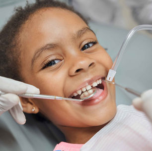A girl smiles while having a dental examination.