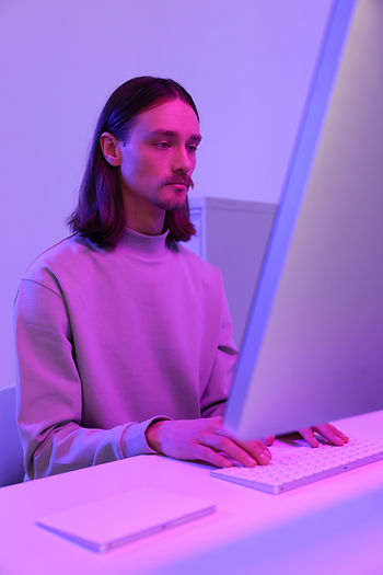 A man under a violet light, working on his PC