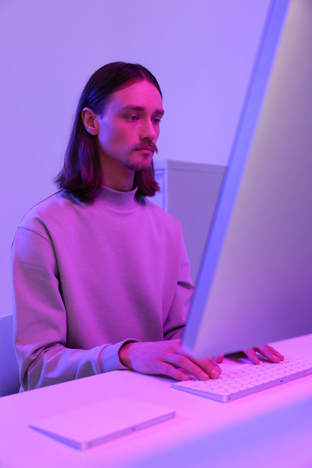 A person on a computer in a modern, neon-lit office environment.