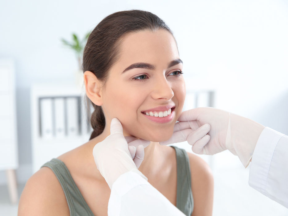 Smiling woman's face examined by doctor; cosmetic procedure in clinic. SISU Beauty Clinic