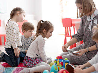 Children in a classroom, gathered around a teacher