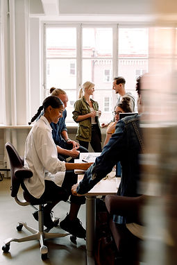 a busy office environment with colleagues around a desk discussing work