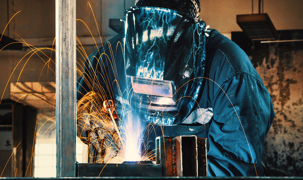 Closeup of worker in blue welding metal plates with a bright gas welding machine and glowing white torch