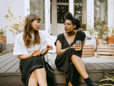 two women talking on a back porch with wine