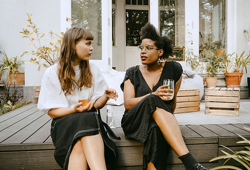 Two women sitting outside enjoying a friendly conversation, conveying the safe space for women to open up, heal, and grow.