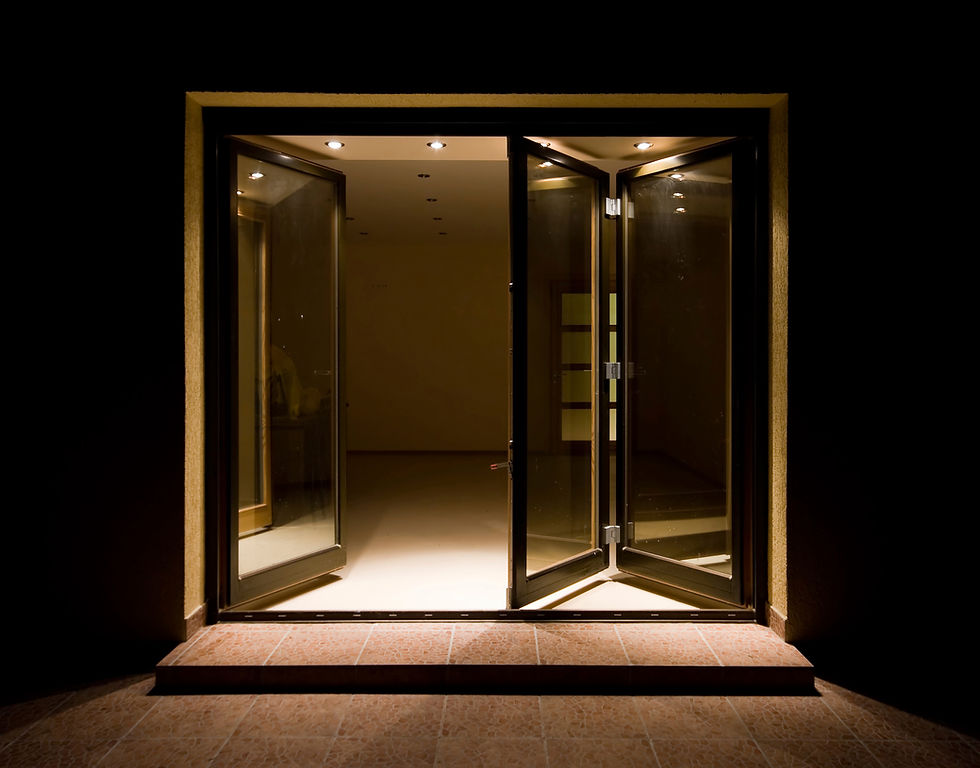 a dark-framed glass bi-folding door system opening into a brightly lit interior space