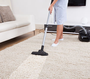 woman cleaning a rug with a vacuum cleaner
