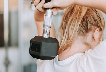 Person laver styrkeøvelse med håndvægt under træning for ryg