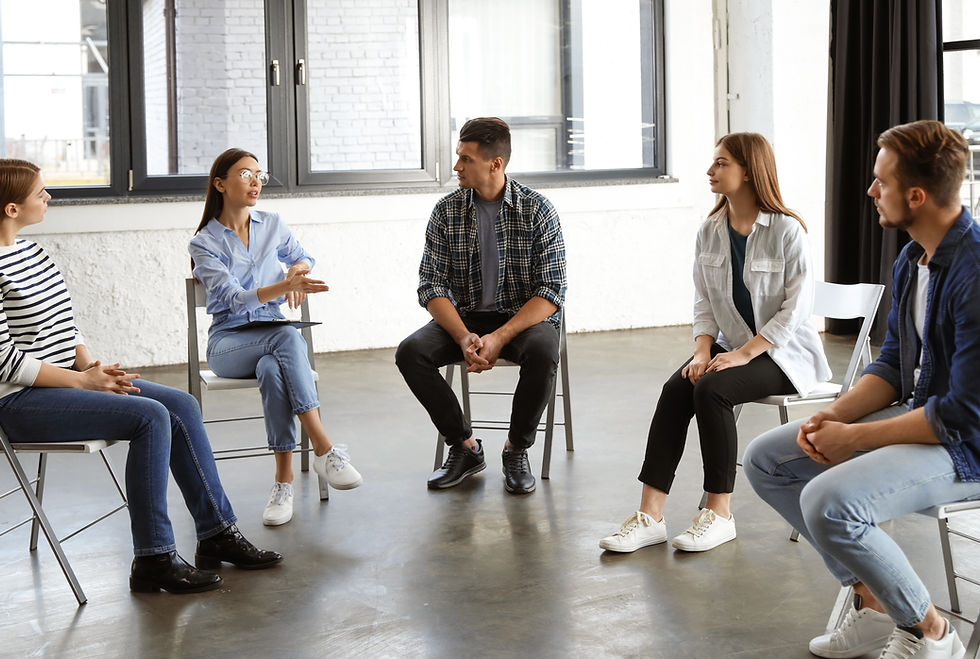 A family of four smiles together while talking with a counselor in a welcoming counseling office.