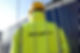 Low view of a security man behind a wire fence wearing a hardhat