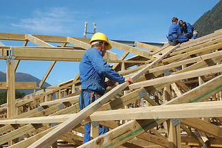 builders working on the roof of a large house
