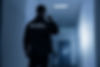 Rear view of a security guard with a flashlight in a building corridor