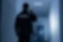 Rear view of a security guard with a flashlight in a building corridor