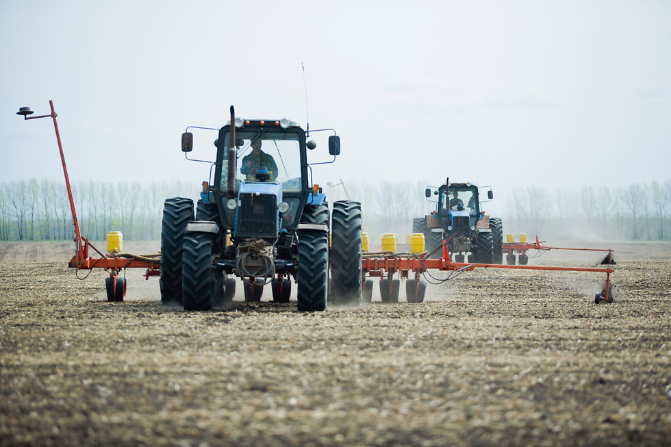 Two blue tractors pulling orange seed drills across a wide field