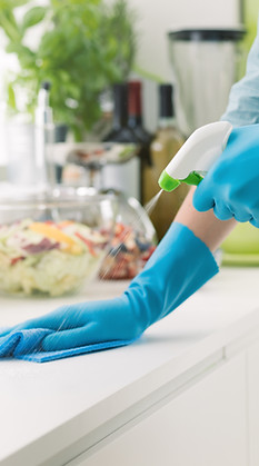 person sanitizing kitchen counter