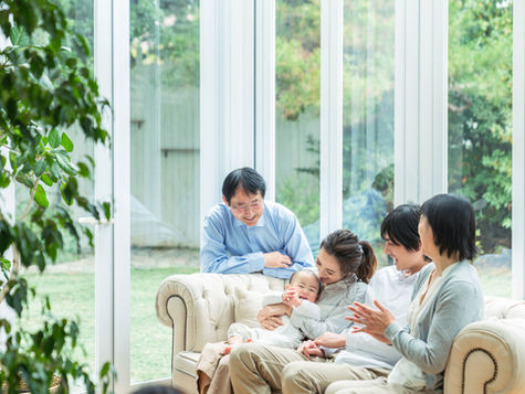 A happy individual at home surrounded by friends and family, symbolizing total well-being and supportive living.