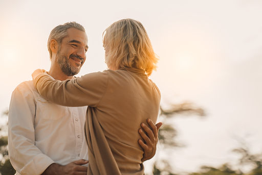 A couple holding each other, man is smiling looking at the lady