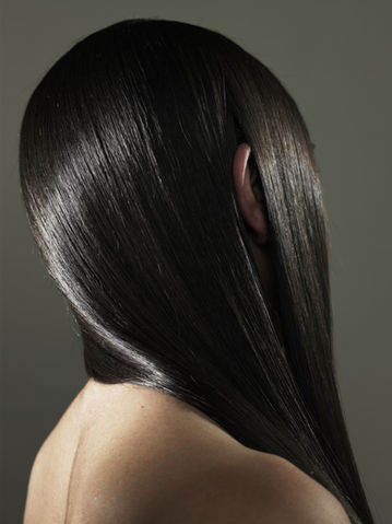 A close-up view of a person's shiny, dark, straight hair from behind.