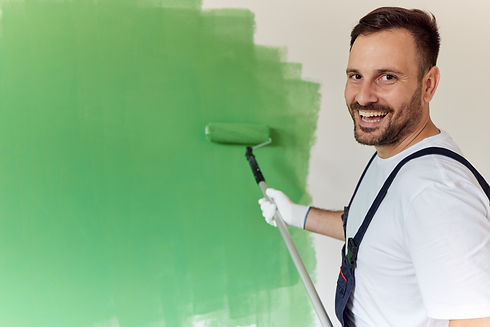 Happy house painter painting the wall in green