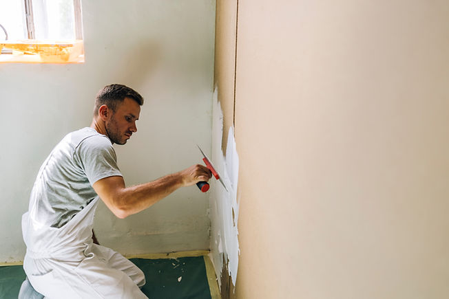 Tradesman smoothing freshly applied plaster along wall edge using trowel