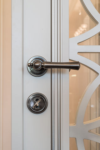 Close-up of a white door featuring a metallic handle and keyhole