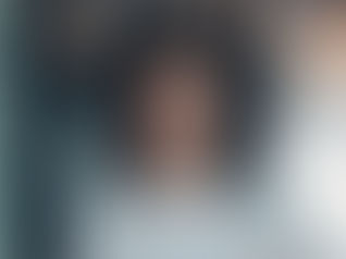 A woman with 4C hair massaging oil into her scalp, showing defined coils and healthy growth.