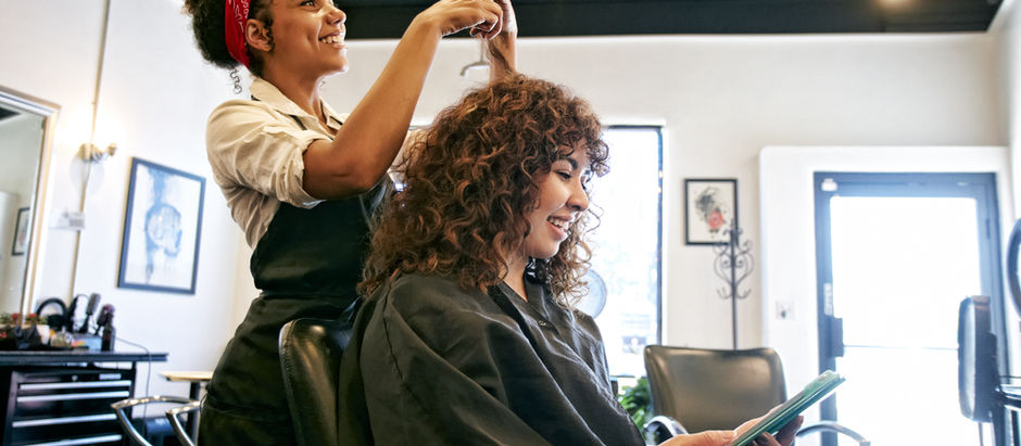 Mulher corta cabelo de cliente em salão de beleza