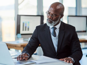 A business owner sits at his desk, annoyed by the number of cold email messages he has received.