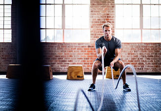 Man exercising with fitness training ropes inside a bright spacious gym studio