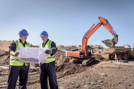 Apprentice builders studying drawings on housing building site
