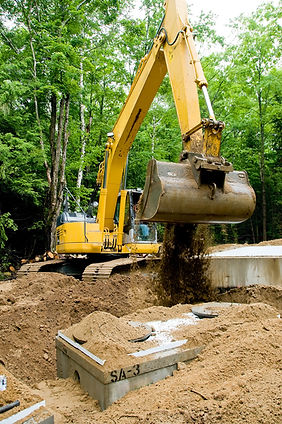 An excavator burying a septic tank at a construction site