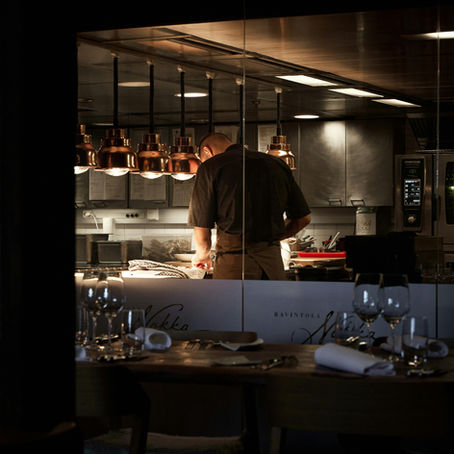 Chef dedicado prepara uma refeição na cozinha cuidadosamente iluminada enquanto se concentra nos detalhes finais.