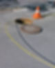 An open manhole with a yellow hose running through it on the street