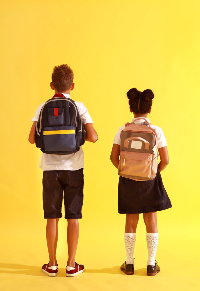 the backs of a boy with a blue backpack and a girl with a pink backpack struggling with not being good enough on the way to school