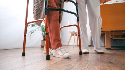 Senior using a walker with assistance from a caregiver.