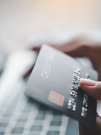 Online shopping made easy: A person holds a credit card near a laptop, ready to make a purchase.