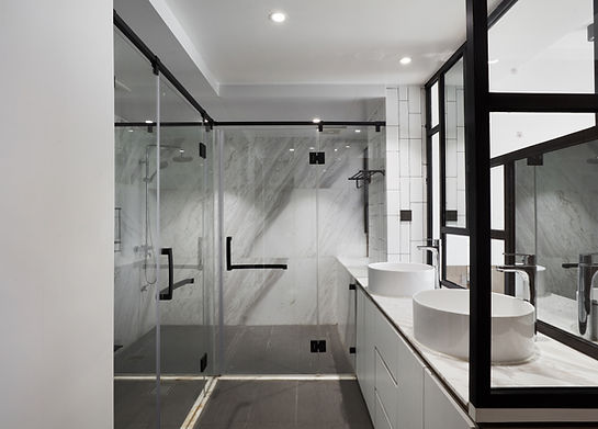 Modern bathroom featuring a glass-enclosed shower, marble accents, and sleek double vessel sinks with chrome fixtures