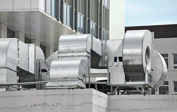 Industrial ventilation system featuring large grey exhaust fans and metallic ductwork on a building rooftop