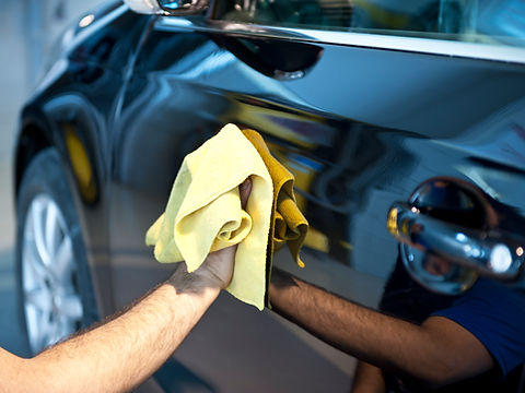 A professional using a cloth to clean a car