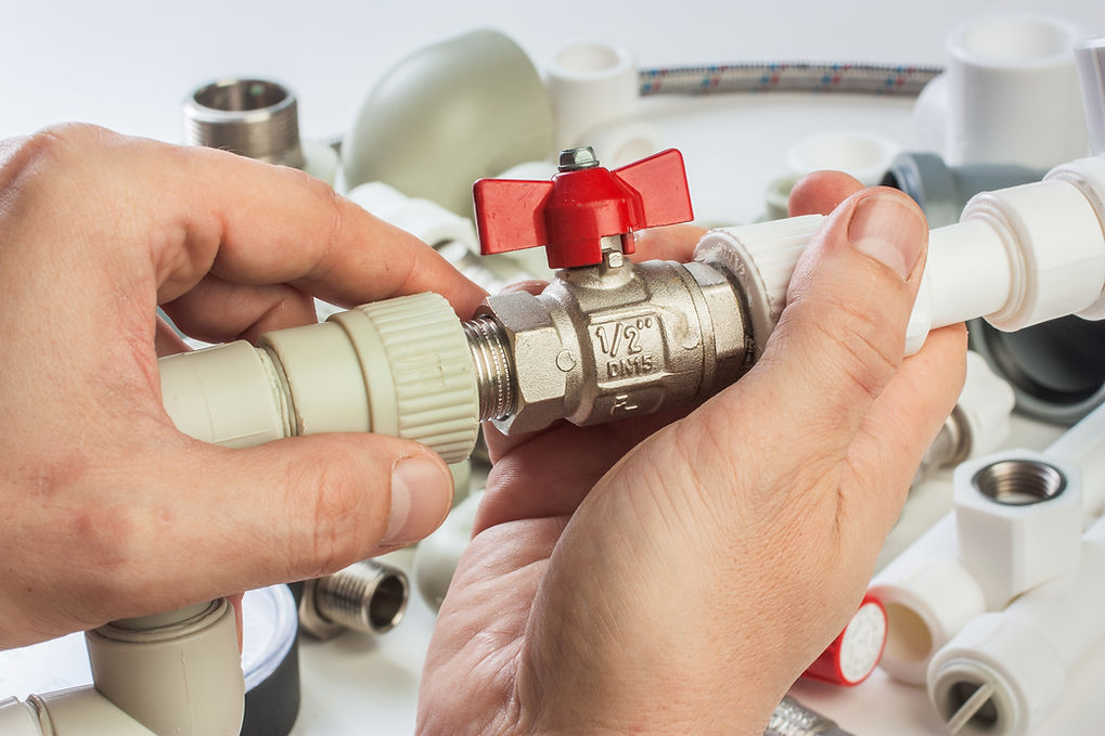 A person using tools to repair a valve on a pipe, focused on the task at hand.