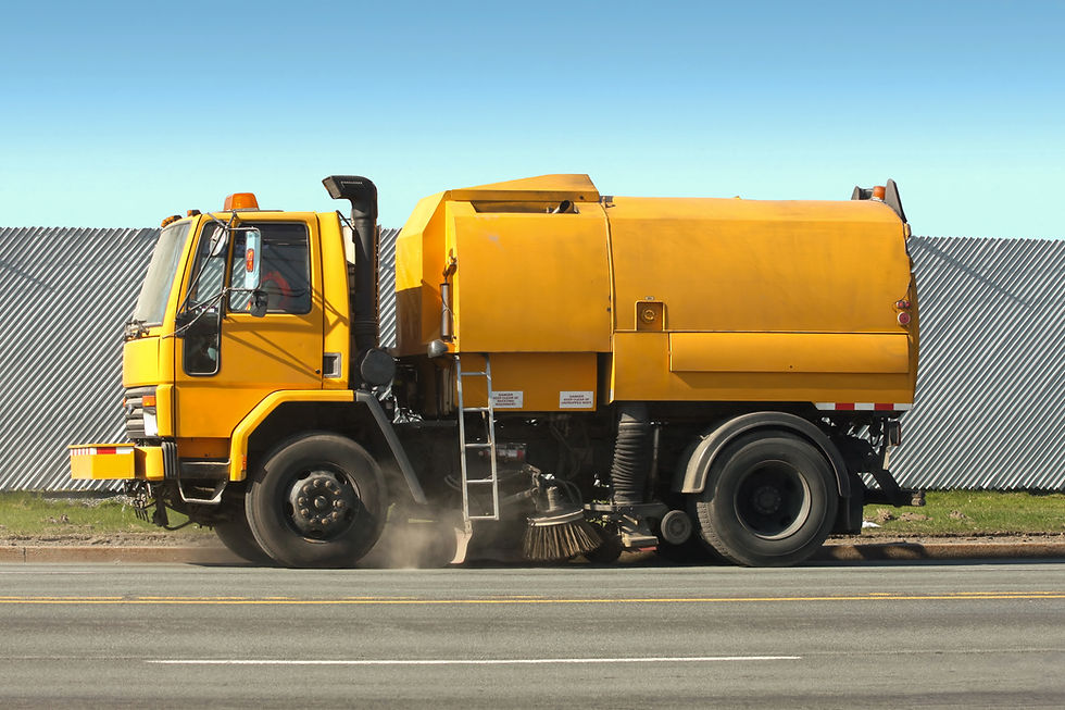 Road sweeper moving slowly as it sweeps and vacuums up road debris on a city street.
