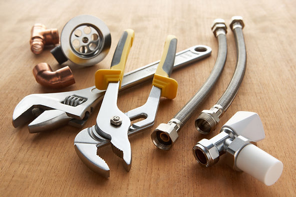 Plumbing tools and materials on wooden floor